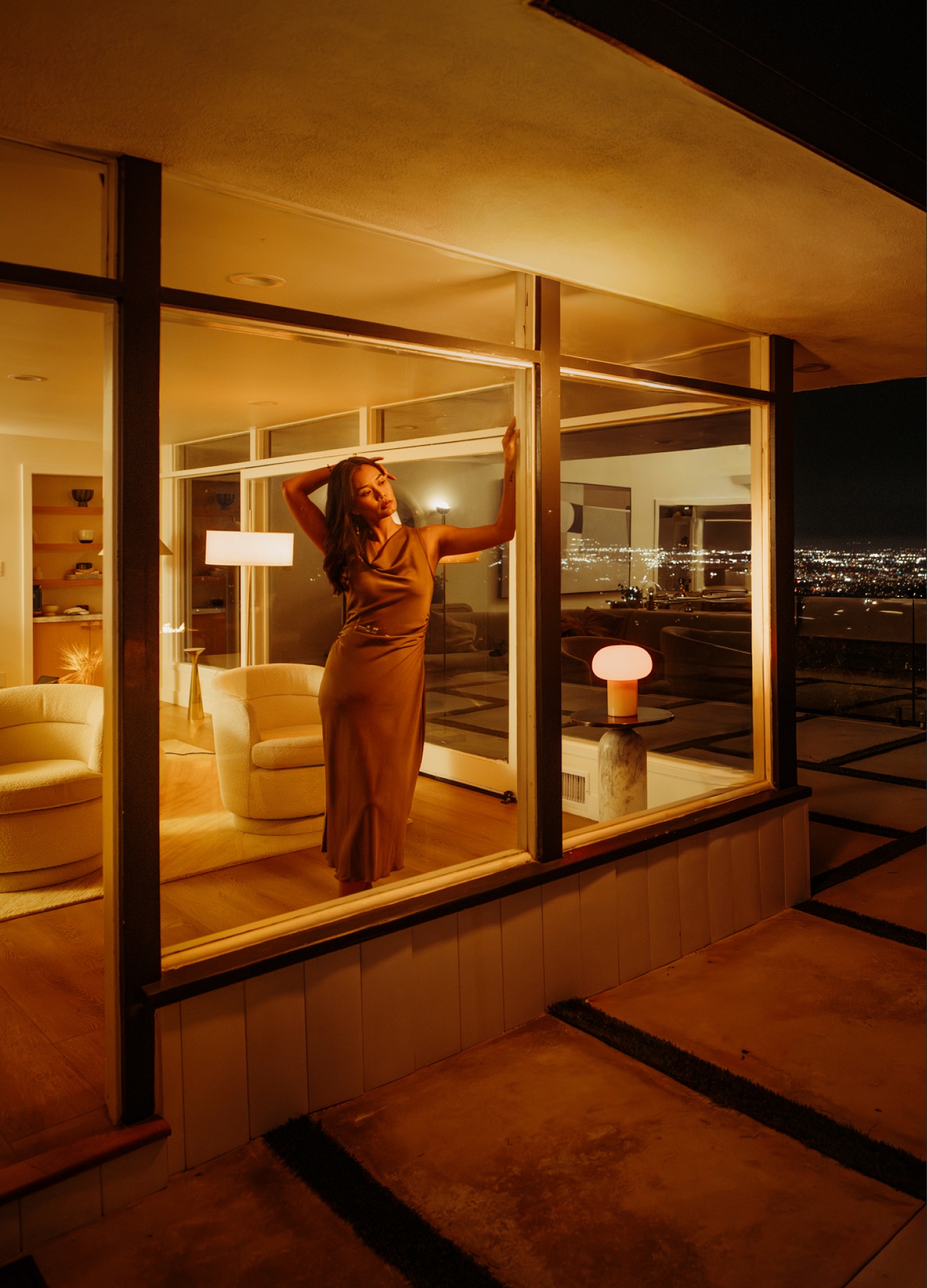 A woman standing in a window under warm LUMIOS lighting
